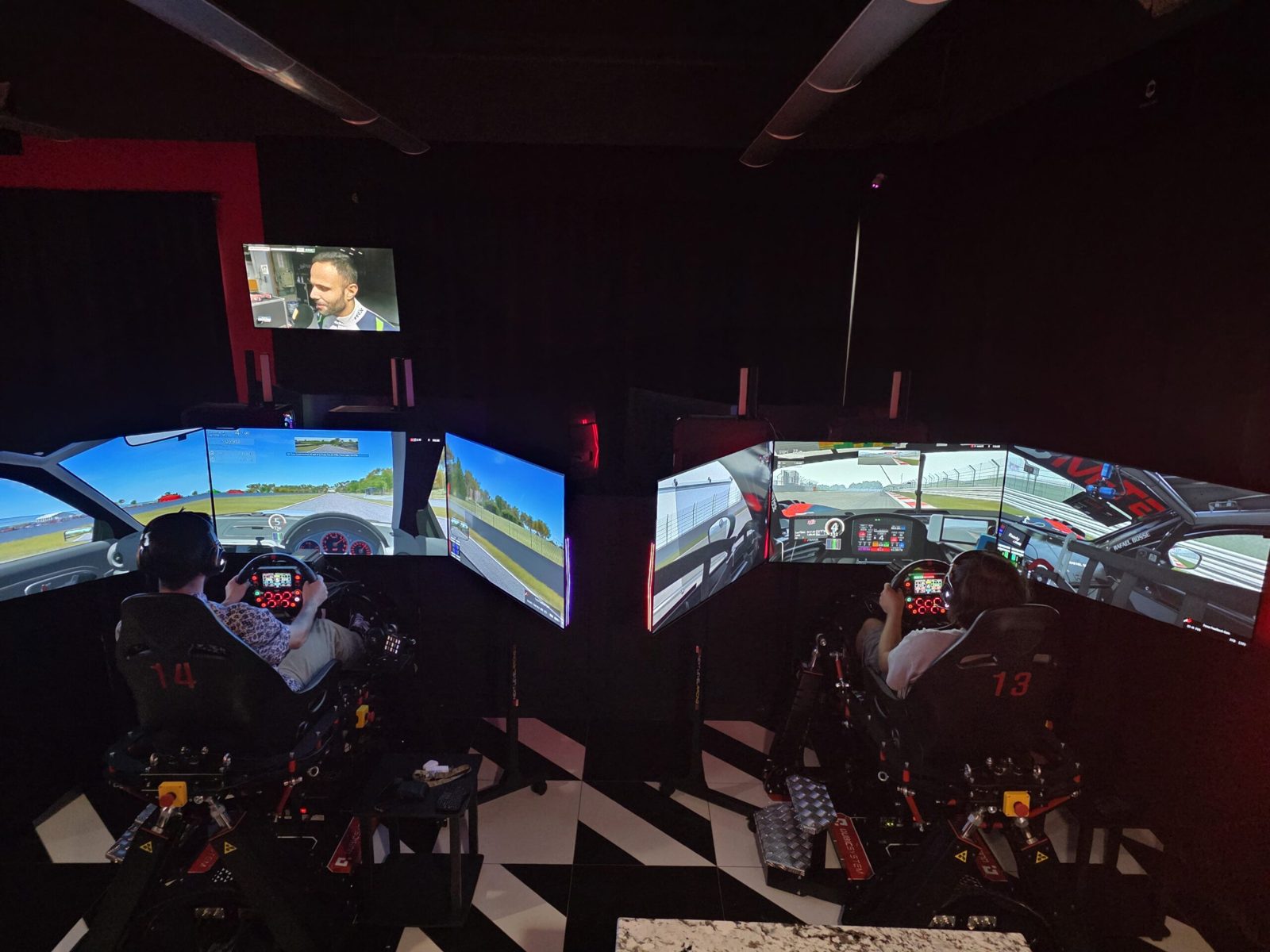 Two drivers racing side by side on full-motion sim rigs at World of Racing Leawood