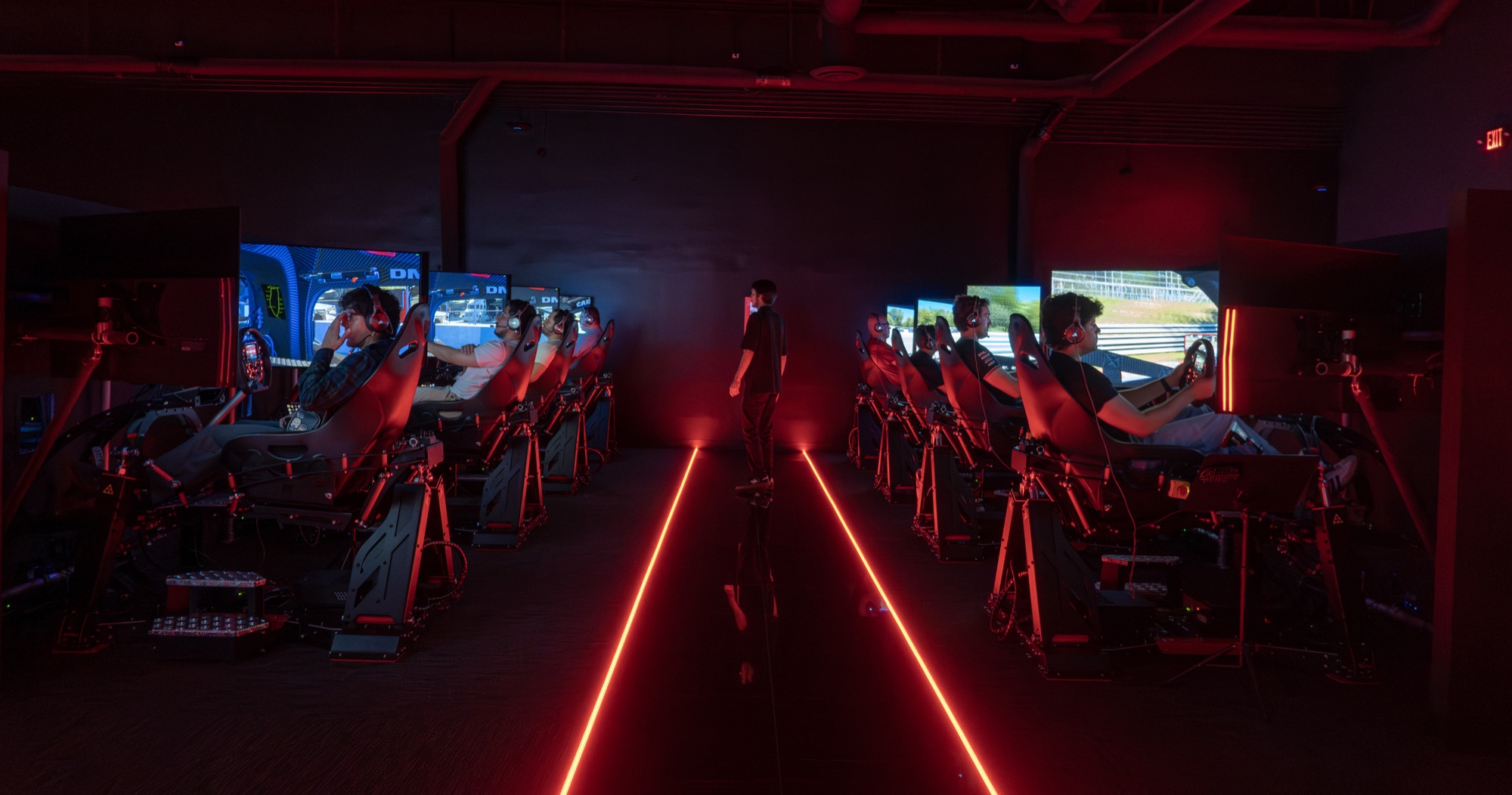 Wide view of the World of Racing Tustin racing floor with rows of full-motion sim rigs